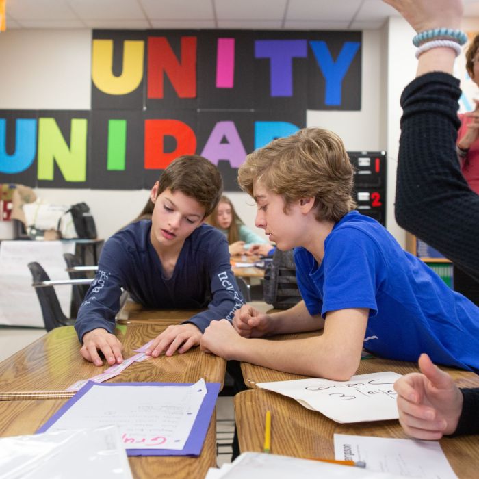 Group of students working together with teacher looking over their shoulders