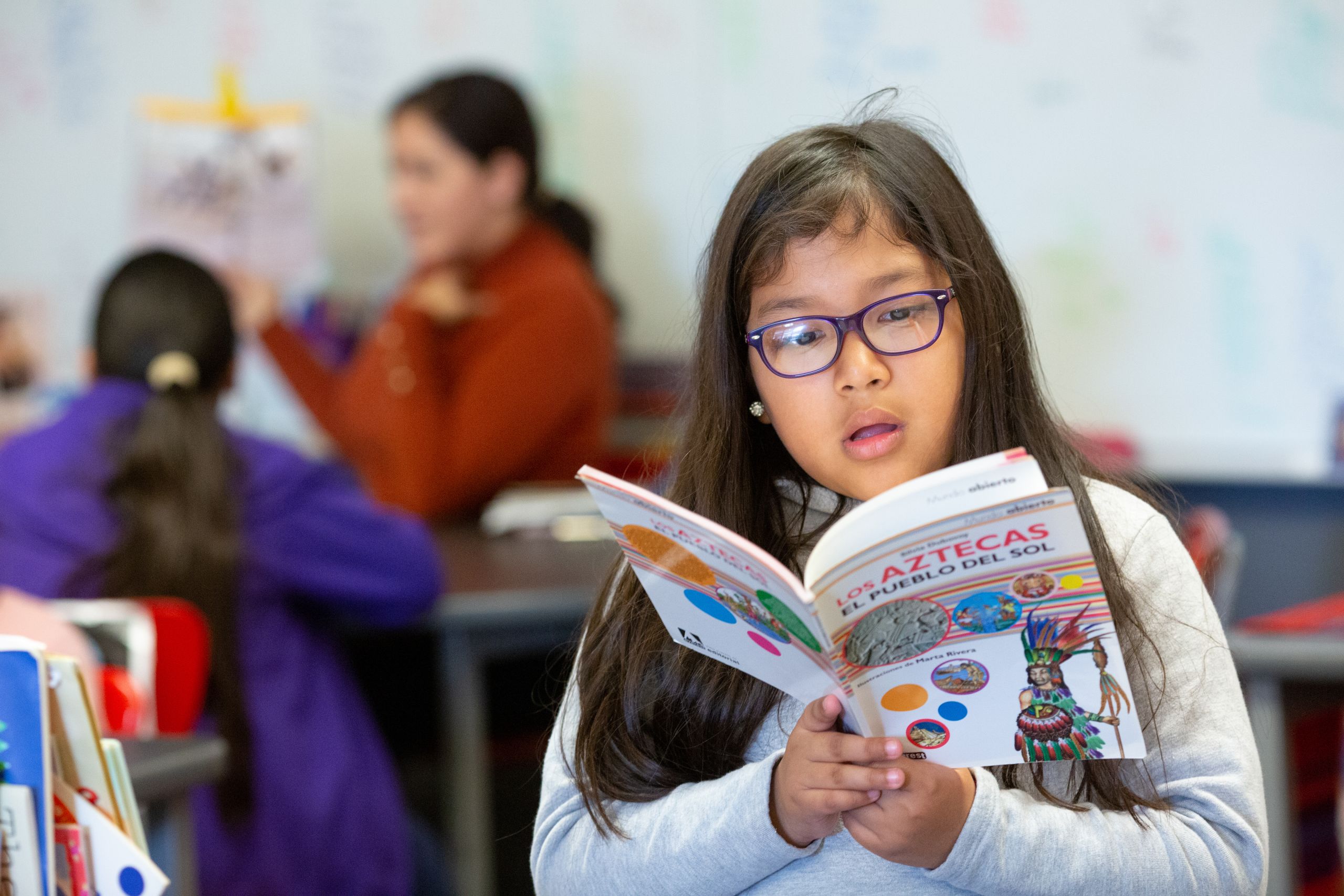 elementary age girl reading a book in Spanish
