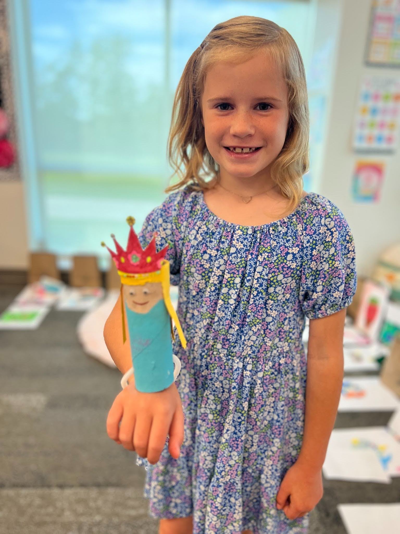 a smiling girl holding a princess made of a toilet paper tube