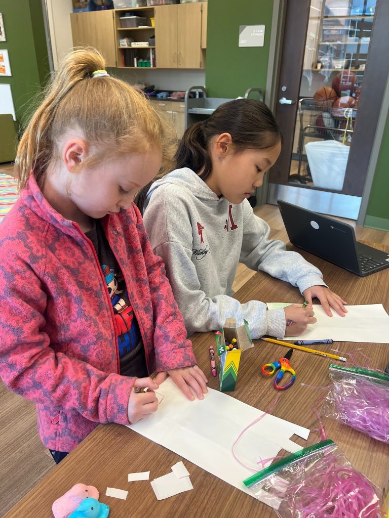 2 elementary aged girls drawing with crayons