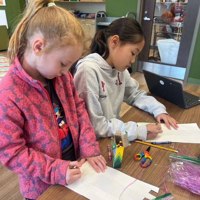 2 elementary aged girls drawing with crayons