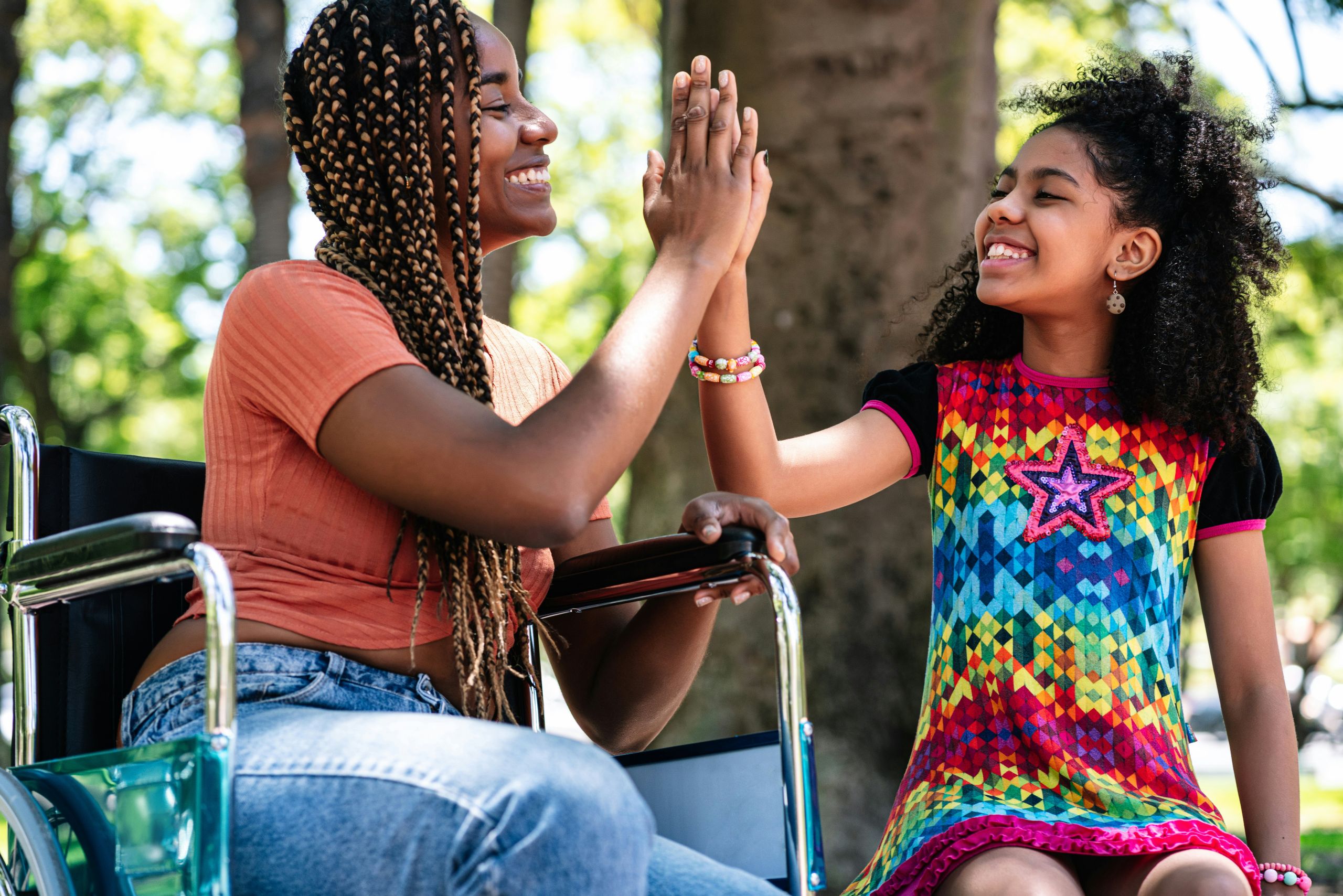 Woman in wheelchair high-fiving pre-teen girl