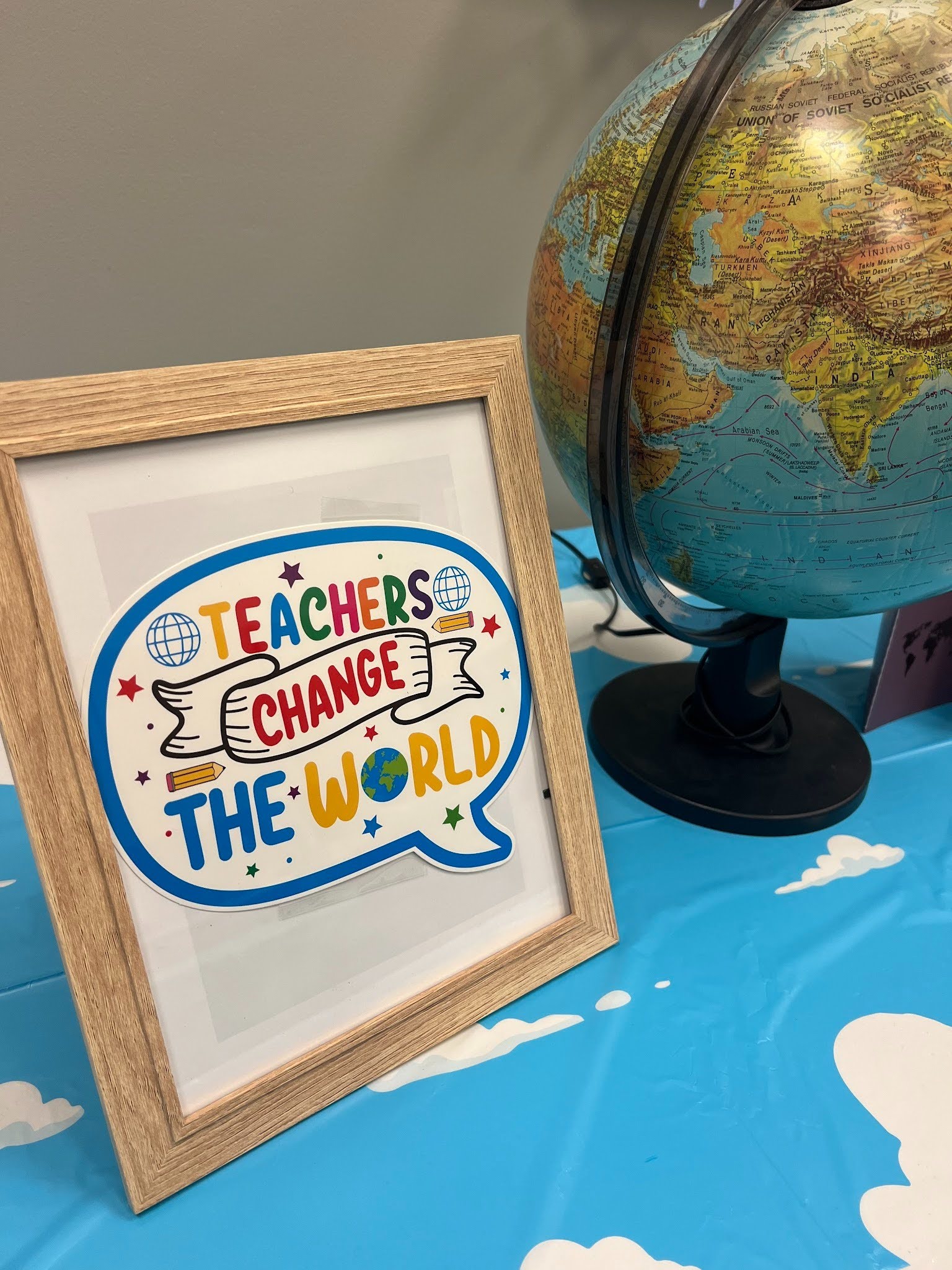 a globe with framed quote next to it that says "Teachers change the world"