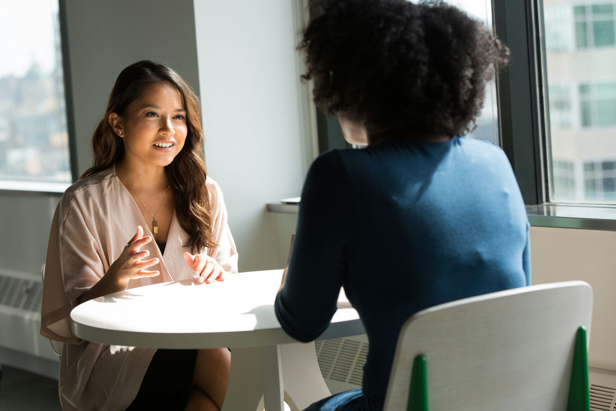 Two women sitting by a window facing each other talking