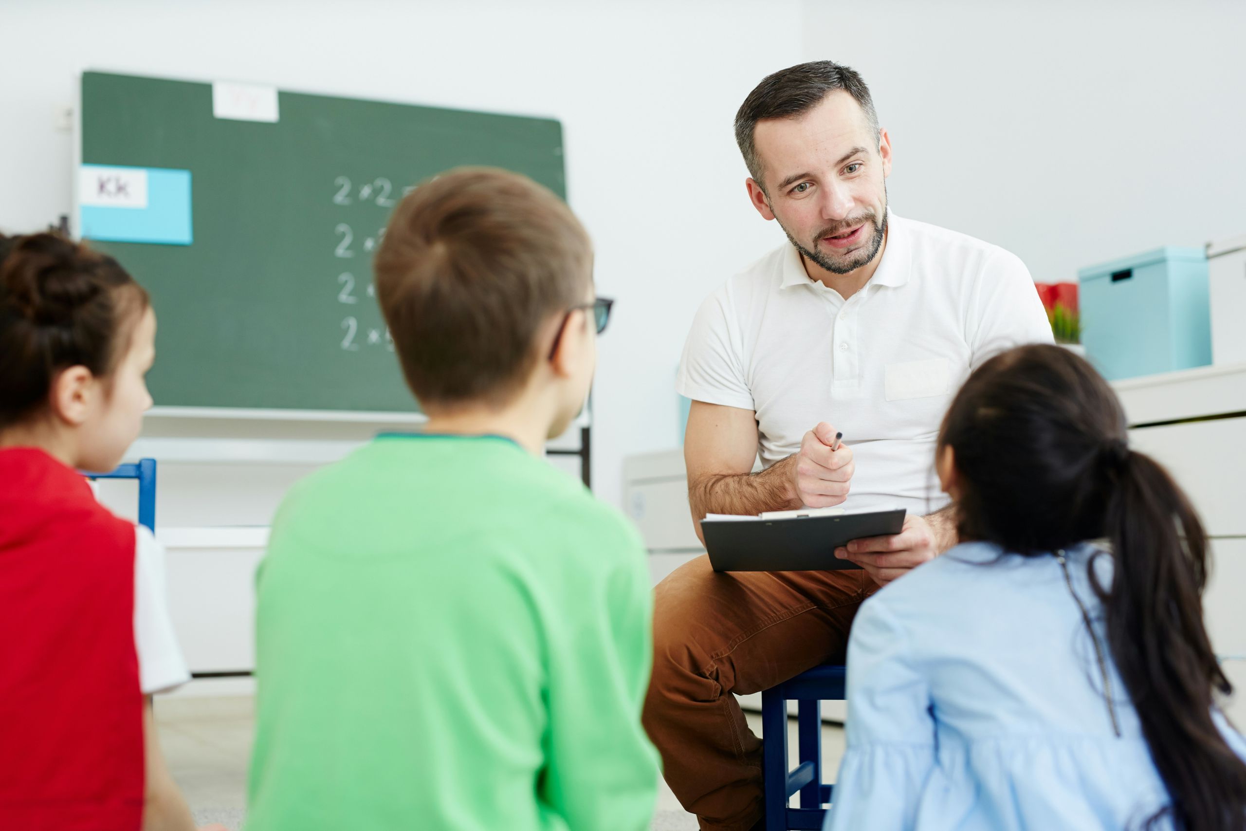 a teacher talking to students while holding a clipboard