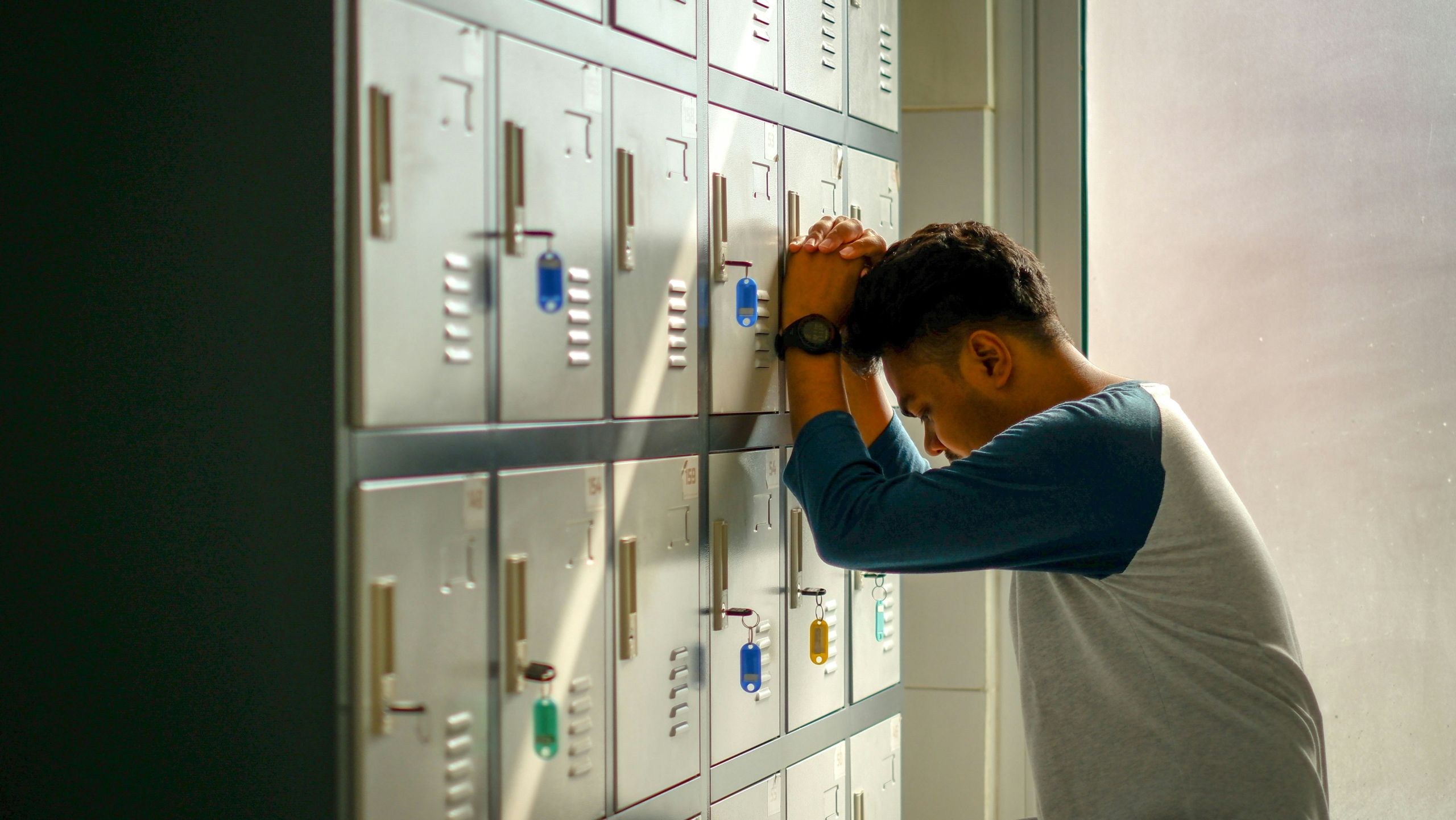 Teenager leaning forehead against lockers