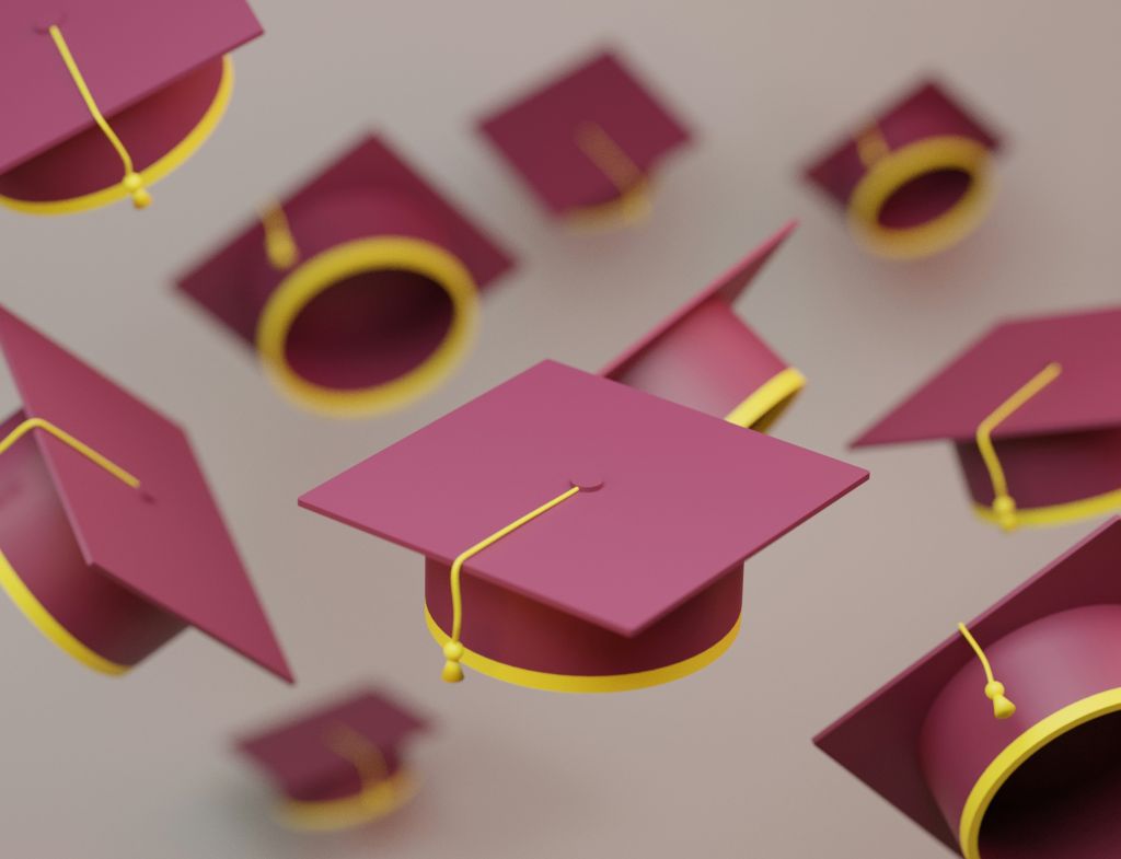 Multiple burgundy graduation caps in the air