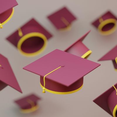 Multiple burgundy graduation caps in the air