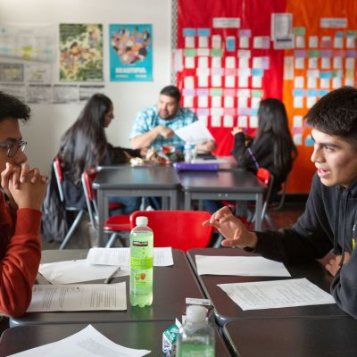 A high school boy explains his research topic to his classmates in an AP research class.