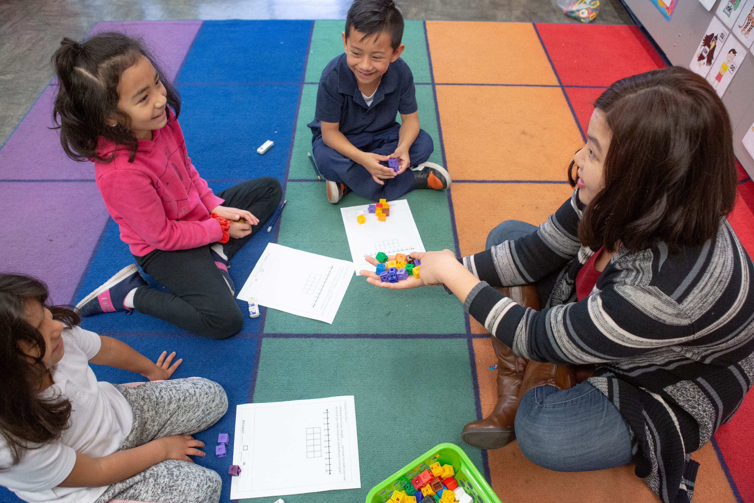 Kindergarten number cubes A kindergarten teacher uses number cubes during a small-group math activity.