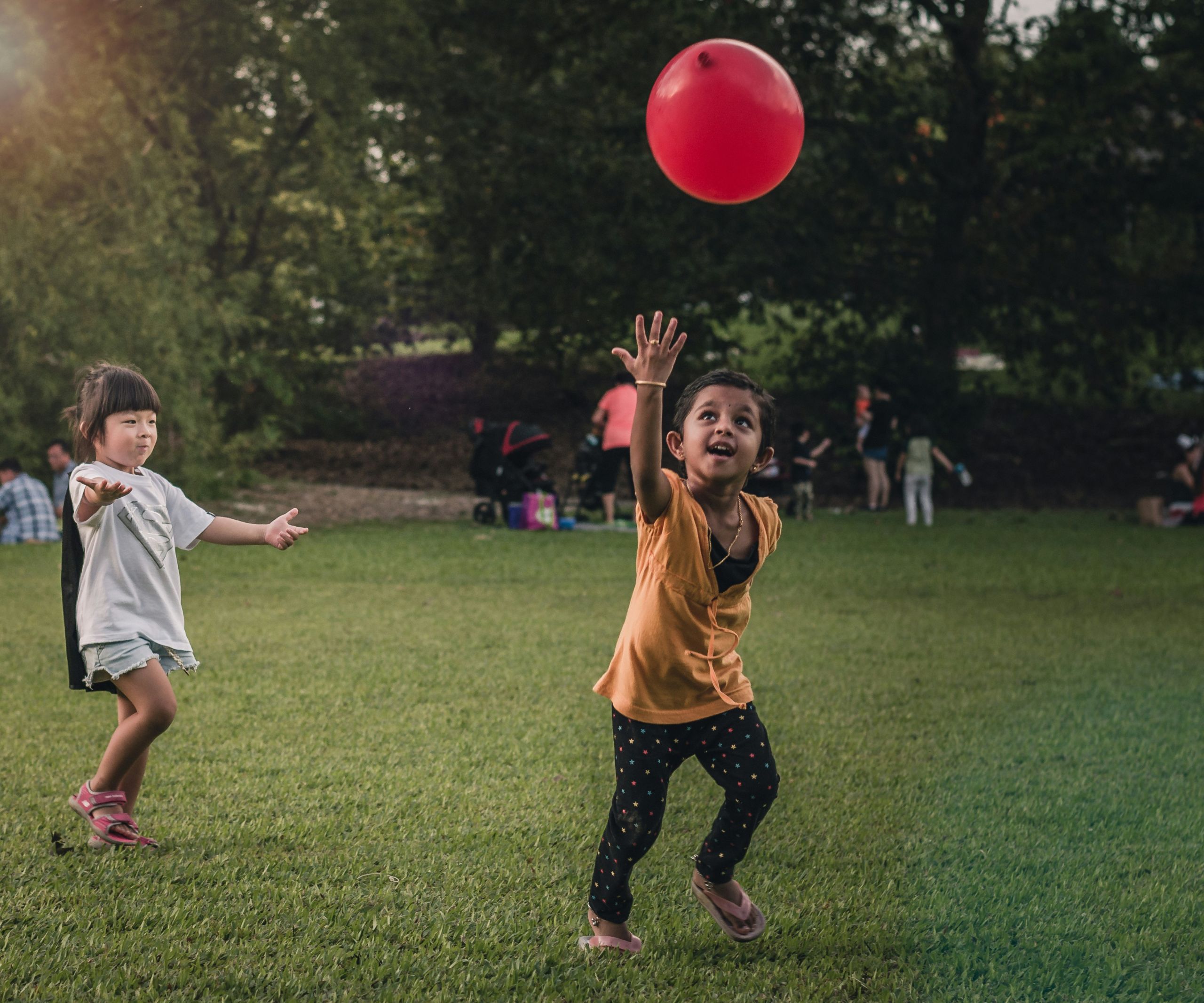 alaric-sim-0N4UJja6jEU-unsplash Two children running chasing a red floating balloon