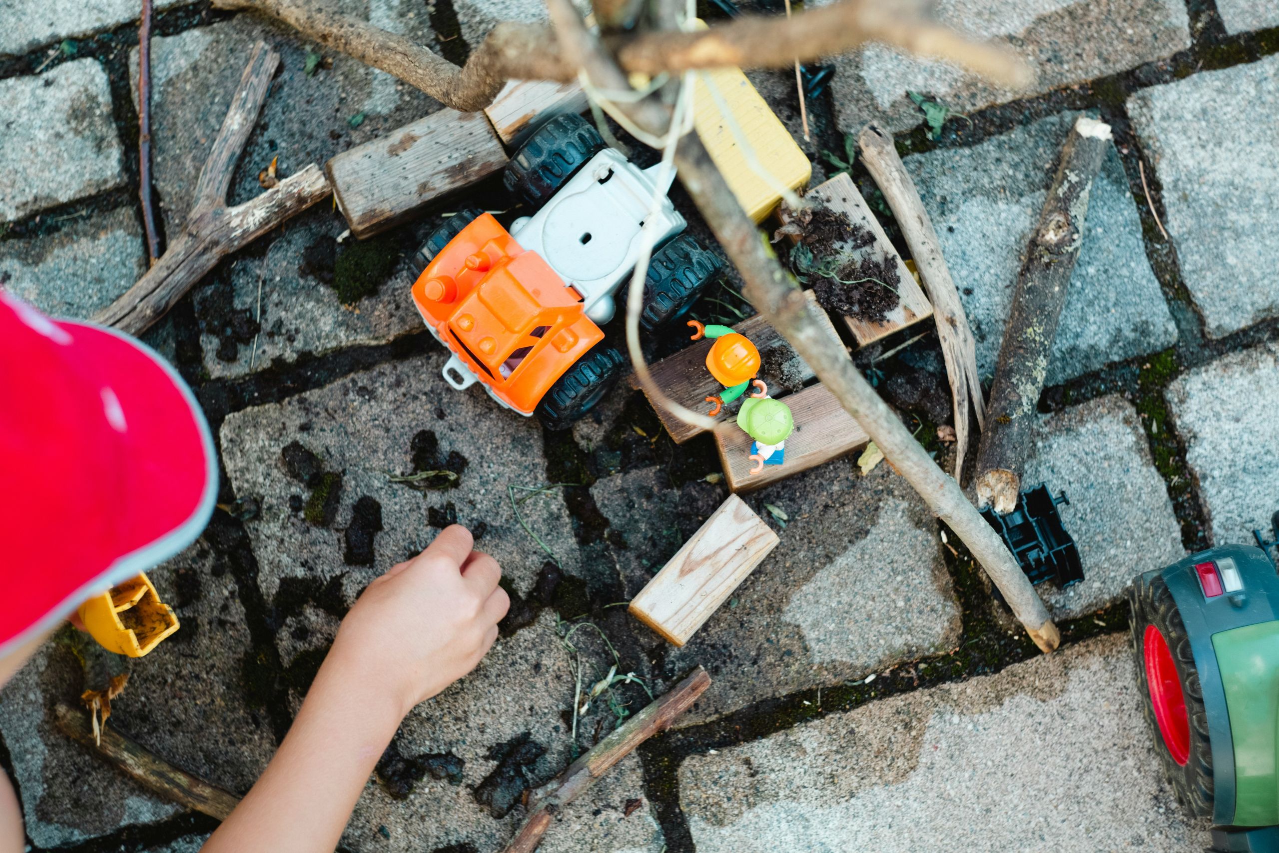 markus-spiske-0WD_wlqIlZU-unsplash a child's hand playing with dirt and sticks and construction toys